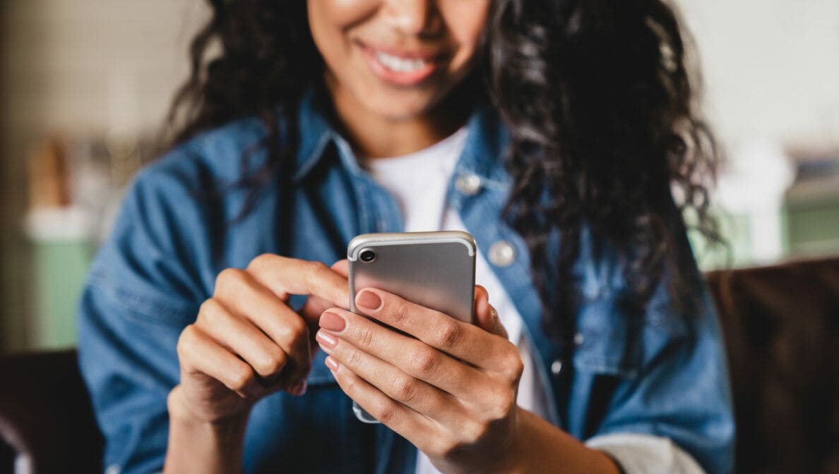 Eine Person tippt auf dem Smartphone, das sie in der Hand hält.