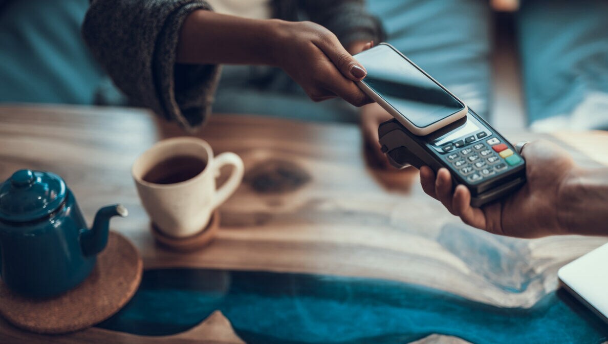 Nahaufnahme einer Hand, die mit einem Smartphone bezahlt.