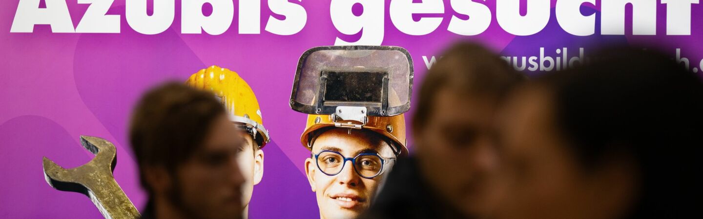 Besucher stehen auf der Jobmesse «KarriereStart» vor dem Schriftzug «Azubis gesucht». (zu dpa: «Studie: Viele Jugendliche könnten schneller in Ausbildung»)