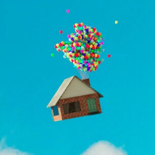 Haus fliegt mit Ballons durch blauen Himmel