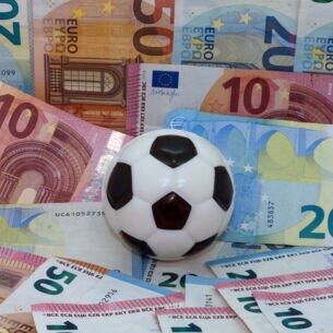 Ein Fußball vor einem Hintergrund aus Geldscheinen
