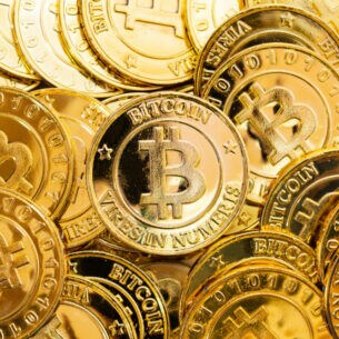 Diverse goldene Münzen, die das international bekannte Symbol für Bitcoin tragen