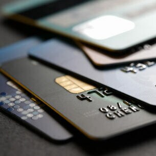Ein Stapel unterschiedlich farbiger Kreditkarten vor dunklem Hintergrund.