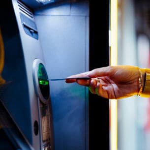 Nahaufnahme einer Hand, die eine Bankkarte in einen Automaten steckt.