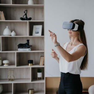 Eine Person steht in einem Wohnzimmer und trägt eine Virtual-Reality-Brille.