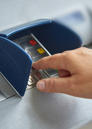 Eine Hand beim Eintippen einer PIN am Geldautomaten