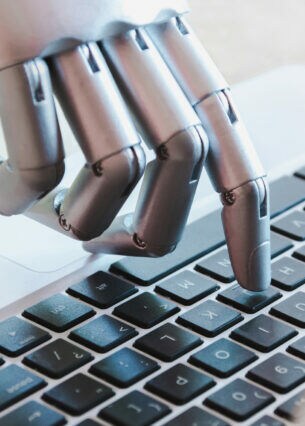 Eine Roboterhand, die auf einer Laptoptastatur tippt