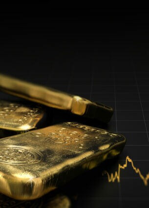 Mehrere Goldbarren liegen auf einem Aktienkurs, dessen Verlauf nach oben geht.