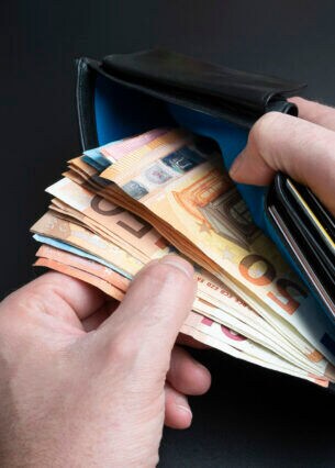 Hände nehmen Geldscheine aus einer Geldbörse
