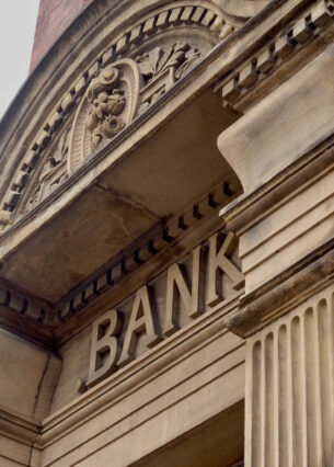 Nahaufnahme eines Gebäudes, über dessen Eingang der Schriftzug „Bank“ steht.