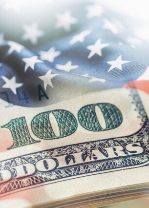 Eine Bildkomposition aus einer US-Dollar-Note und der US-amerikanischen Flagge.