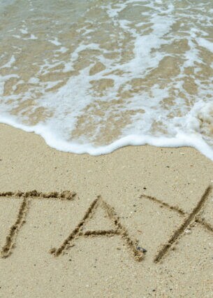Am Meer ist in den Sandboden das Wort TAX geritzt.