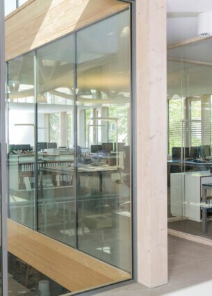 Büroräume mit Glaswänden auf einer höheren Etage über einer Werkstatt.