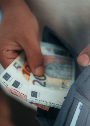 Eine Person nimmt Geldscheine aus einem Portemonnaie .