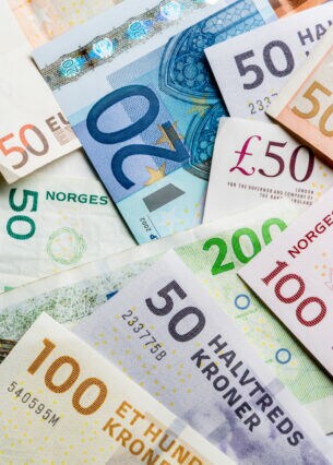 Übereinanderliegende Banknoten verschiedener europäischer Währungen, darunter Euro und dänische Kronen.